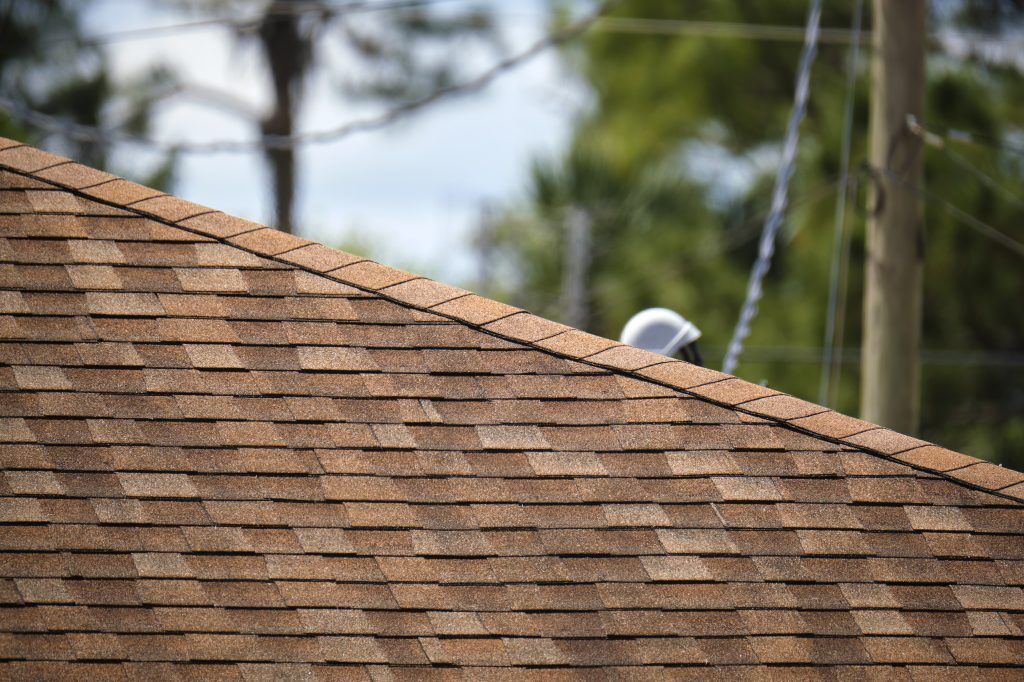 closeup of house roof top covered with asphalt or bitumen shingles. waterproofing of new building